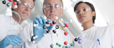 A female and two male scientists are looking at a molecular model